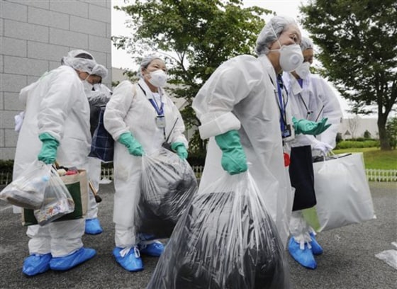 Relatives clad in protective gear Friday bring out belongings of nursing home&nbsp;residents evacuated in Okuma, the Japanese town where the damaged Fukushima Daiichi nuclear power plant is located.